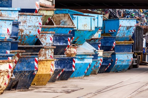 A skip outside a residential street in Upminster with recycling bins nearby